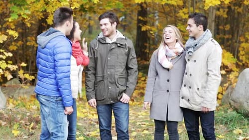 Smiling friends talk and laugh together on a beautiful autumn day in the park