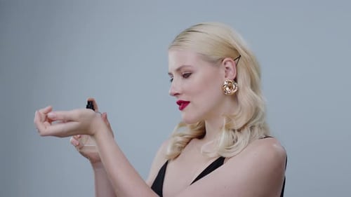 Elegant Woman Sprays and Smells Perfume on Wrist