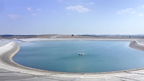 Aerial shot of an agricultural water reservoir surrounded by fields. Irrigation concept