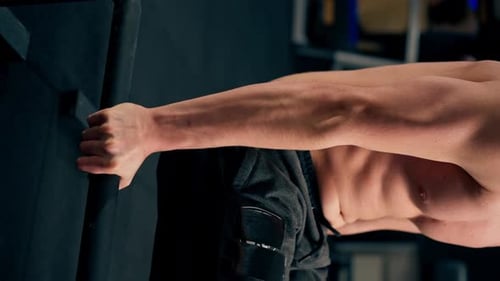 Vertical Video Close Up in a Sports Club Guy Trainer in Black Sweatpants is Doing an Exercise on the