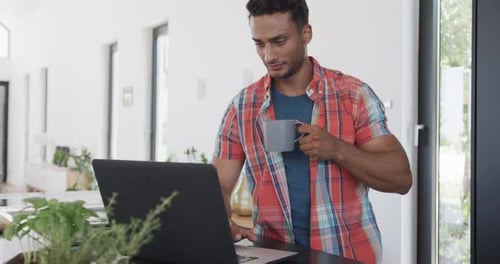 Man Works on Laptop with Coffee at Home