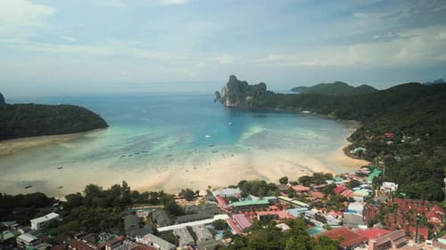 Panoramablick auf einen ruhigen Strand mit smaragdgrünem Wasser und felsigen Klippen in Thailand bei klarer Sicht