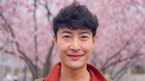 Smiling Young Adult with Cherry Blossoms in Spring