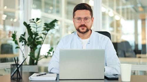 Confident Businessman Working on Laptop in a Modern Office