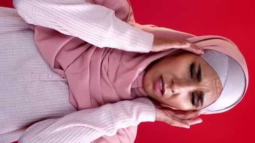 Woman in Hijab Suffering Headache, Isolated on Red
