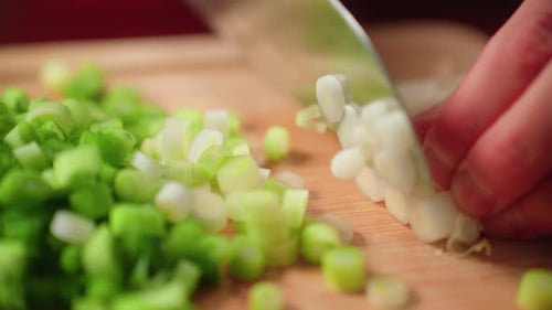 Cutting up green onion by hand on cutting board