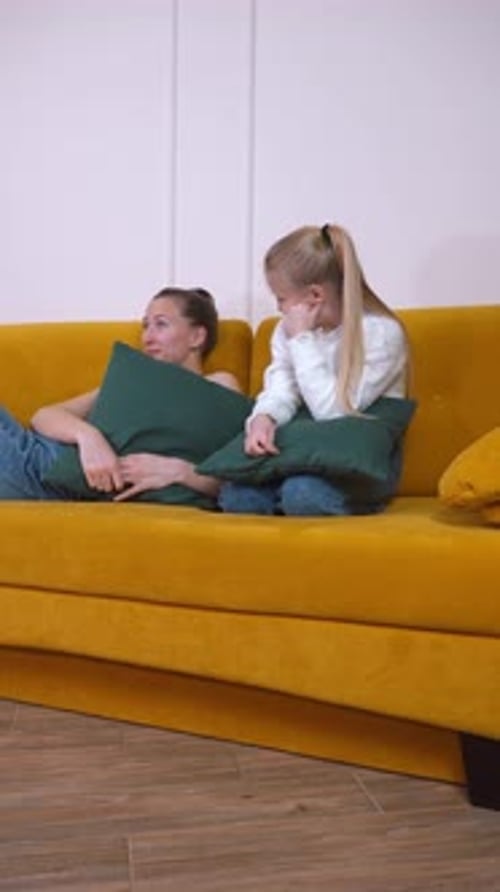 Woman and Girl Relaxing on Sofa Together Indoors