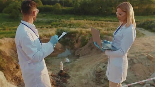 Umweltexperten aus nächster Nähe verwenden Laptop in Schutzkleidung, arbeiten an Landhilfe, sprechen Chemikalien und