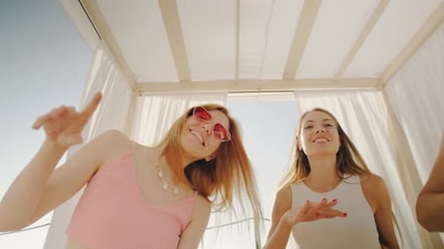 The Image Captures a Group of Young Women Enjoying a Carefree Summer Party in a White Beach Cabana