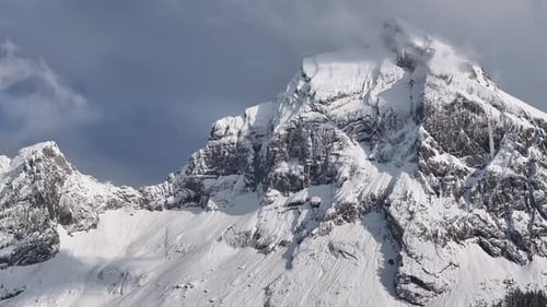 Vue aérienne du sommet enneigé de Fronalpstock avec des falaises escarpées et un ciel partiellement nuageux à Glar