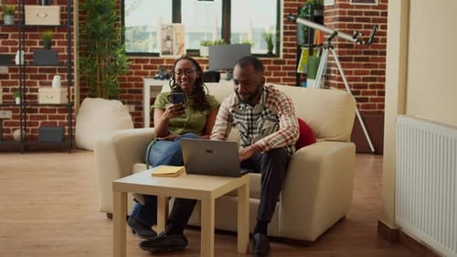 Couple Working on Laptop and Using Phone Indoors