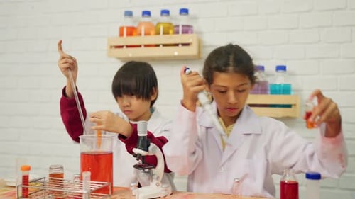 Front view of young scientist boy and girl enjoy to learn and practice to do the experiment school