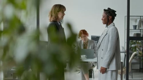 Women Shake Hands in Modern Office Setting