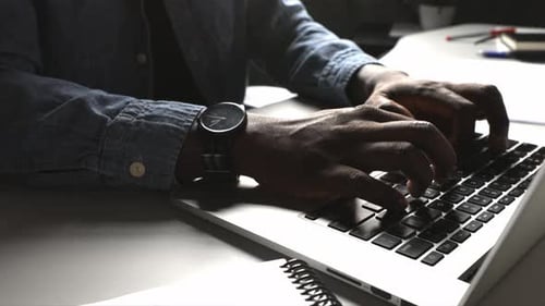 African american businessman typing quickly on laptop keyboard indoors