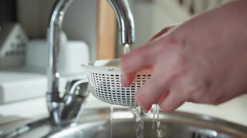 Gros plan d'une personne rinçant des baies sous le robinet dans une scène d'évier de cuisine