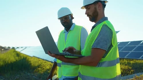 Close Up African American and Caucasian Engineers Walking with Laptop on the Solar Farm in Special