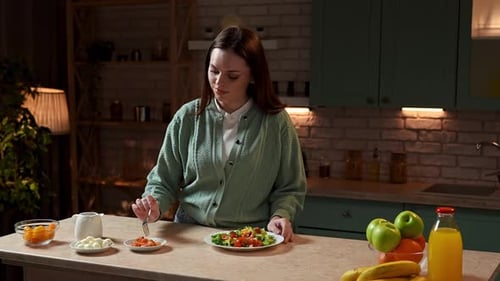 Woman enjoys healthy fresh salad preparation in kitchen