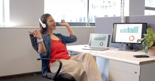 Hearing beat, woman lifting headphones and swaying, highlighting data on PC at office, copy space