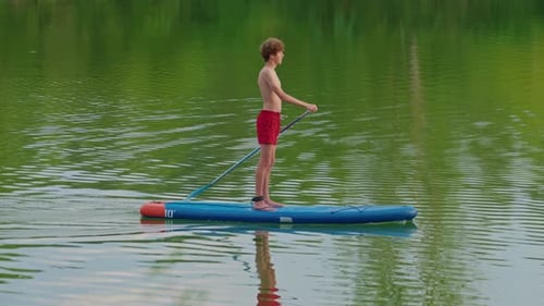 Alone Boy Floating on Stand Up Paddle Board in Lake in Summertime Standup Paddleboarding Surfer Rows
