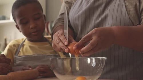 Children and Adult Breaking Eggs into Bowl Together