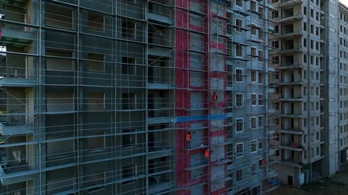Los constructores trabajan de frente al edificio, se apoyan en el andamio