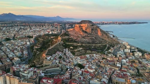 Aerial drone view of the Santa Barbara Castle surrounded by buildings on the coast of Alicante, Spai