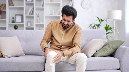 Man Experiencing Knee Pain on Sofa