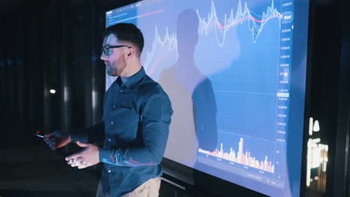 Young Adult Explaining Data on Glowing Monitor