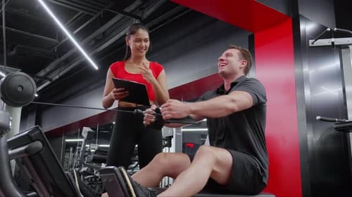 Man Works Out with Trainer at the Gym