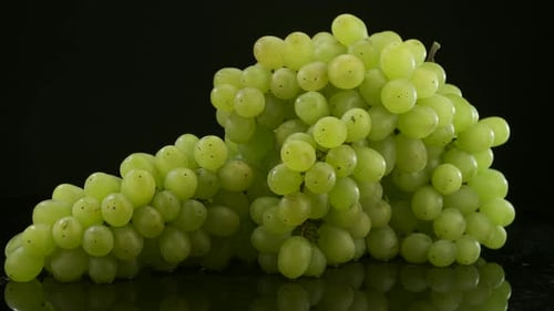 Fresh Green Grapes on Reflective Black Surface