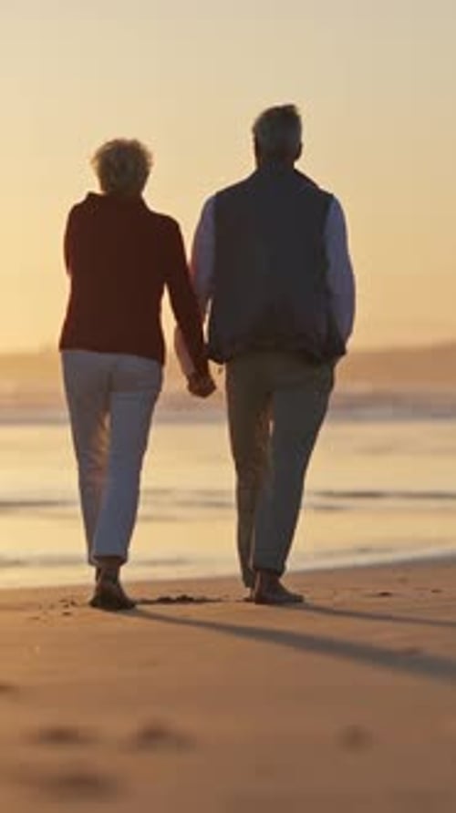 Elderly Couple Walking on Beach at Sunset