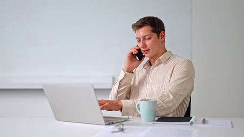 Young Man Works and Talks on Phone