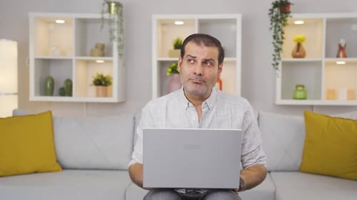 L'homme qui regarde un ordinateur portable n'est pas motivé et s'ennuie.