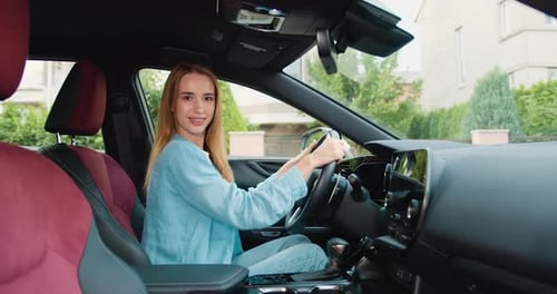 Smiling Woman Driving Car in Suburban Setting
