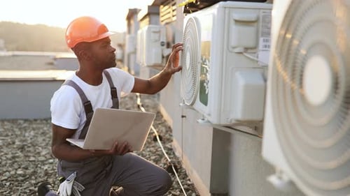 Engineer Inspecting Air Conditioning Units on Rooftop