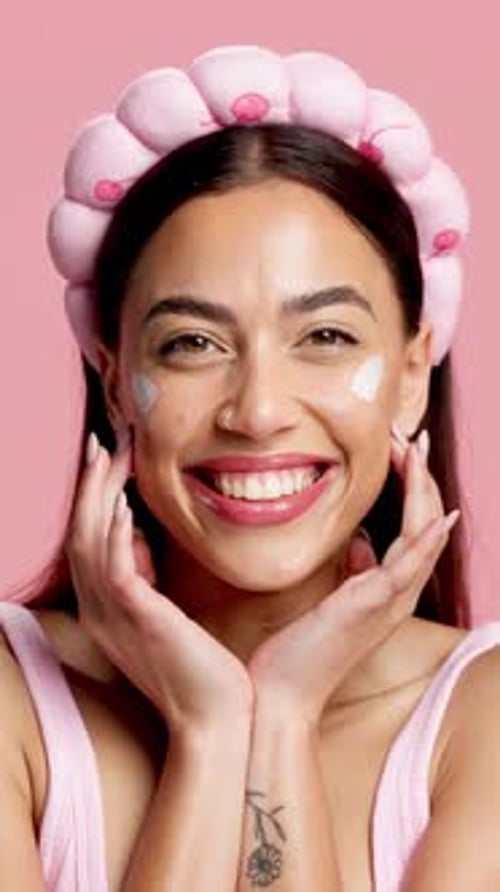 Happy woman, skincare cream and face in studio, headband and pride on pink background