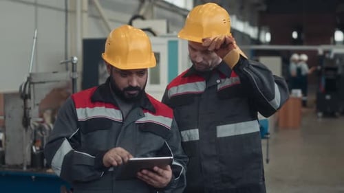 Factory Technicians Looking at Digital Tablet and Discussing Workflow