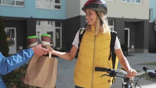 Close Up of Happy Woman on a Bike Delivering Coffee and Food in Paper Bag to Customer Man Home