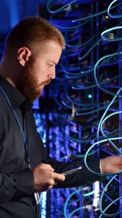 Man With Smartphone Inspecting Servers