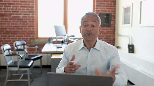 Mature Businessman Video Chatting At Laptop In Office