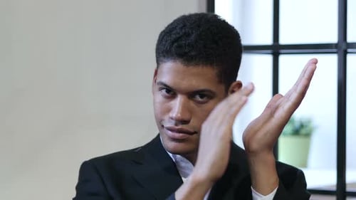 Young Adult Clapping with Serious Expression Indoors