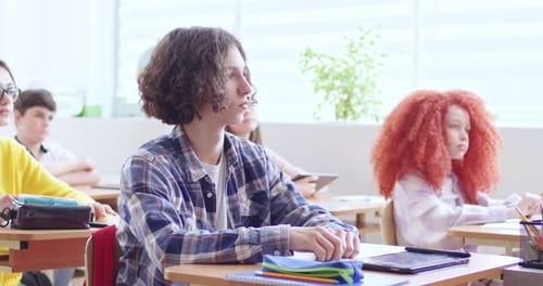 Students Raise Hands in Bright Classroom Setting