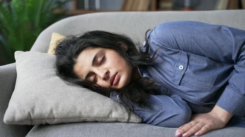 Sleeping woman lying comfortably on gray couch indoors