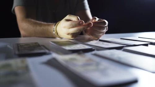 Man in Handcuffs Gesturing at Table With Money