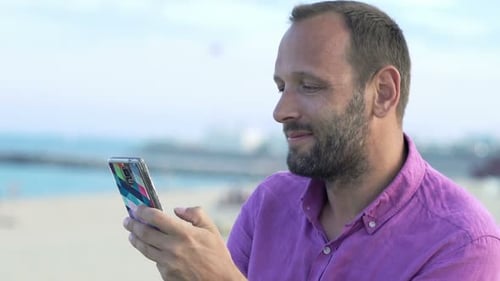 Young man texting on smartphone enjoying the summer coast in the city