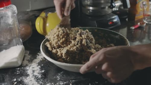 Baker's Hand Mixing Cookie Dough With A Wooden Spoon - close up, static shot
