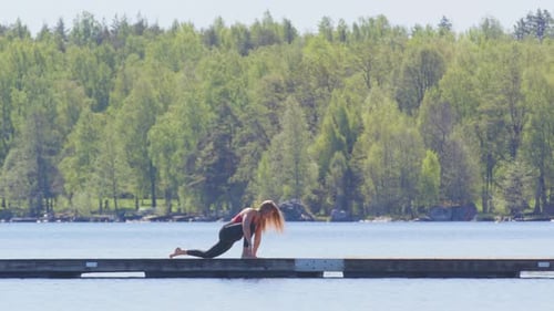 Femme yogi sur un quai flottant en bois sur le lac faisant une séquence de yoga, vue latérale large