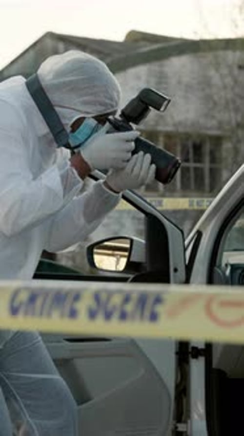 Investigator Photographs Car Behind Crime Scene Tape