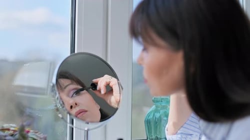 Middle Aged Woman Doing Makeup Applying Mascara Looking in Mirror