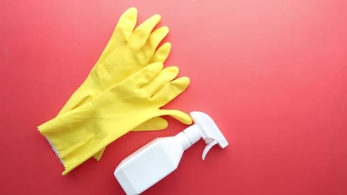 Yellow Gloves and Spray Bottle on Red Background